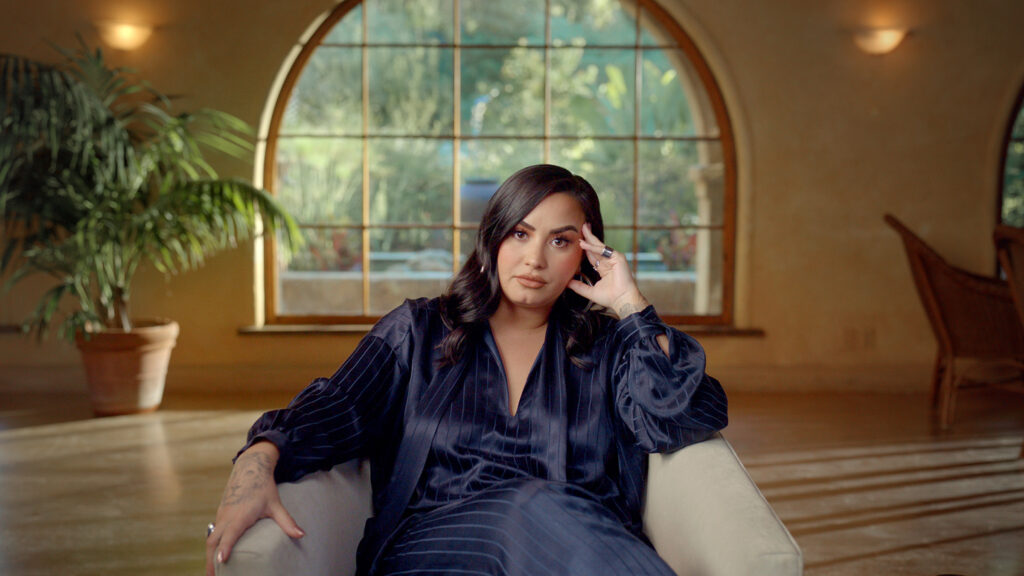 Demi Lovato sat in living room for interview in documentary Demi Lovato: Dancing with the Devil on Youtube