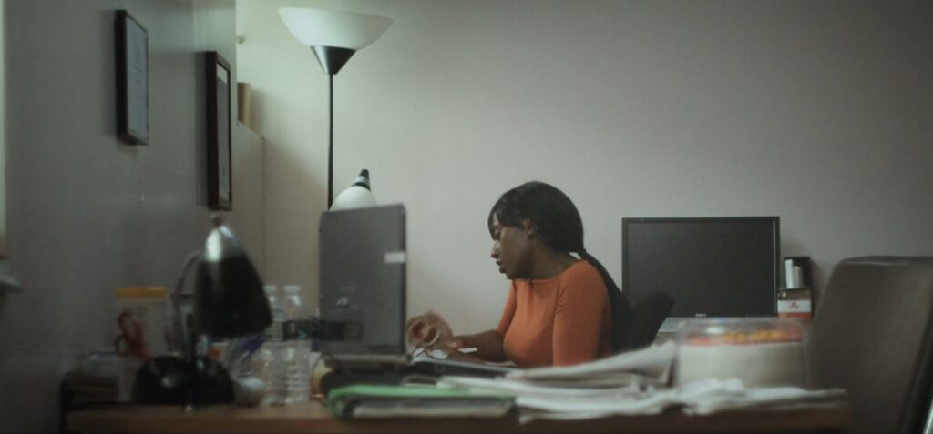 Sarah (Mensah) sits in her cramped Columbia graduate student office in Queen of Glory